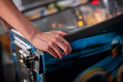 Woman pressing button on pinball machine