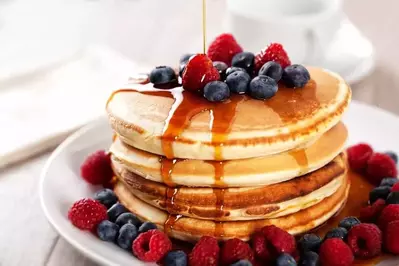 Pancakes covered in berries and syrup.