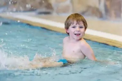 A young boy splashing around in an indoor pool.