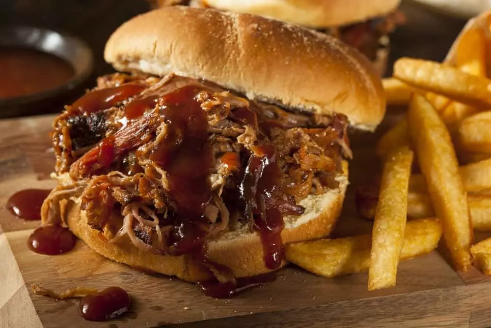 A BBQ pulled pork sandwich with french fries.