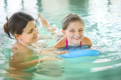 A mother and daughter having fun at an indoor pool.